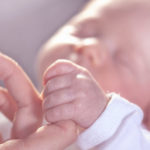 Newborn baby holding finger