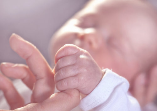 Newborn baby holding finger