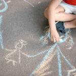 Child drawing on the pavement with coloured chalk