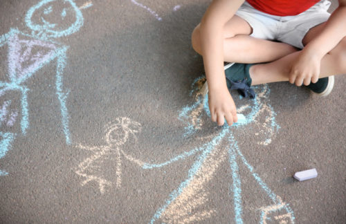 Child drawing on the pavement with coloured chalk