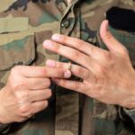 Man in military uniform removing wedding ring.