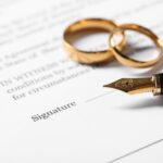 Close up of a fountain pen and wedding rings sat on a contract.