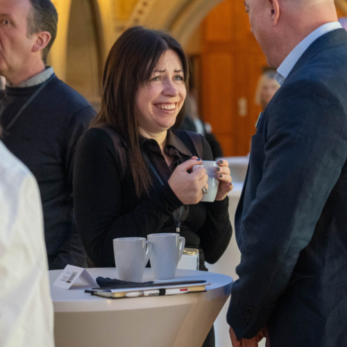 Conference attendees participating in discussion by a table.