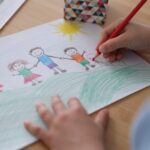 child drawing a colourful picture of family