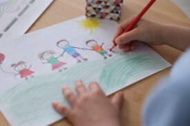 child drawing a colourful picture of family